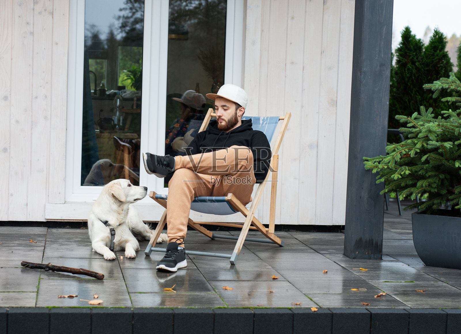 一个年轻人和一条狗在他的乡间别墅附近休息。照片摄影图片