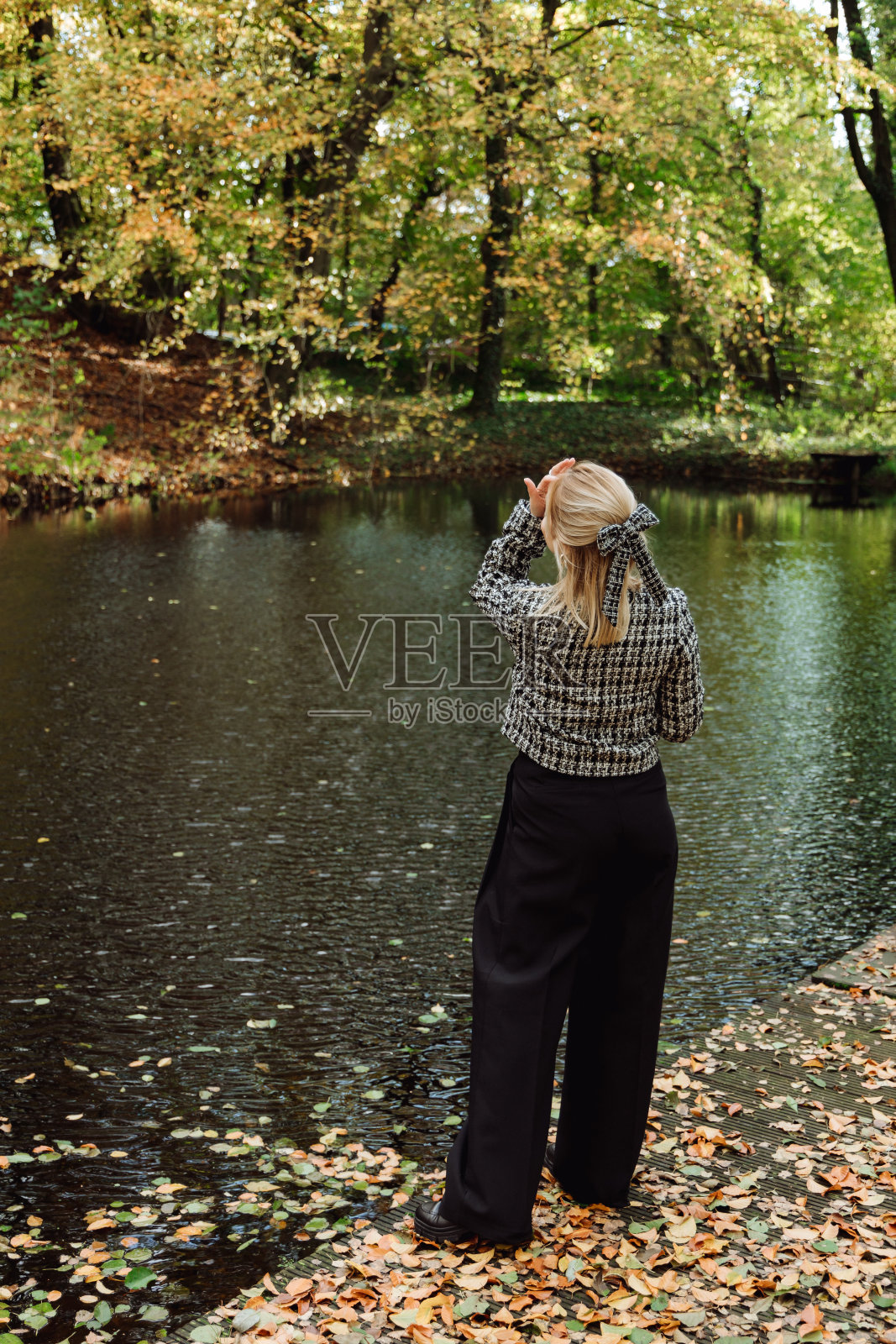 在一片秋林的背景下，一个女孩站在湖边照片摄影图片