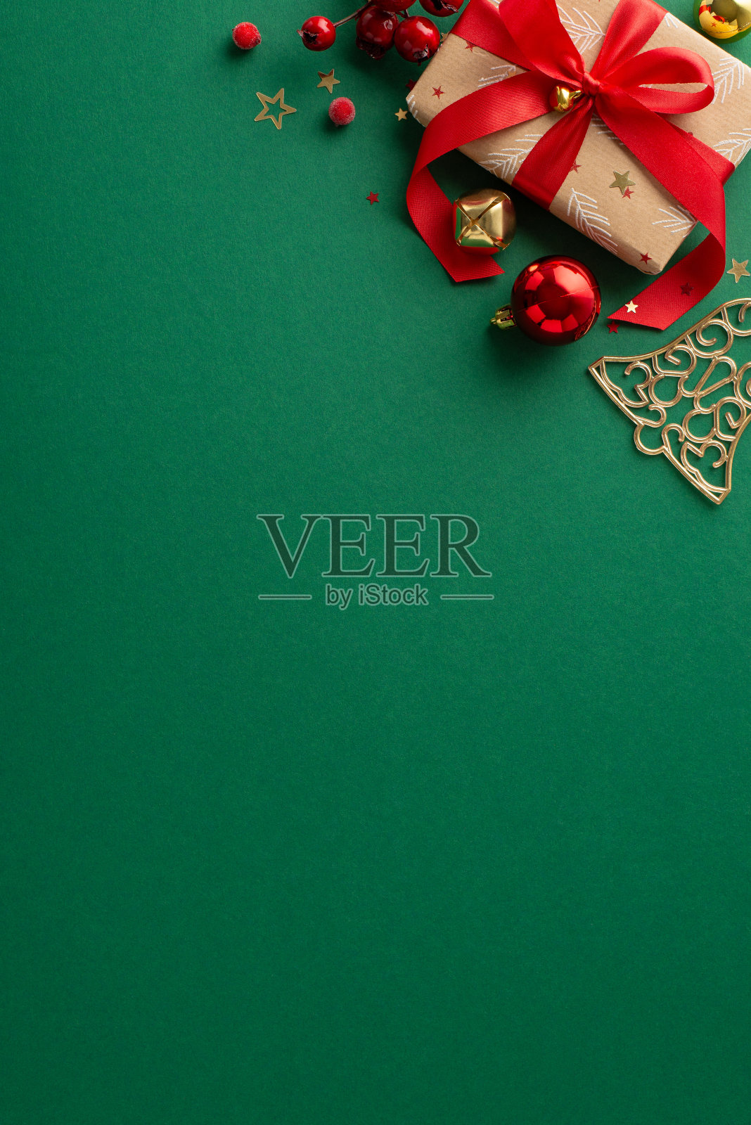 这是准备的季节。俯视图垂直快照的工艺纸礼品盒，节日的小装饰品，槲寄生，叮当铃和绿色背景的五彩纸屑。为你的节日短信或促销留出空间照片摄影图片