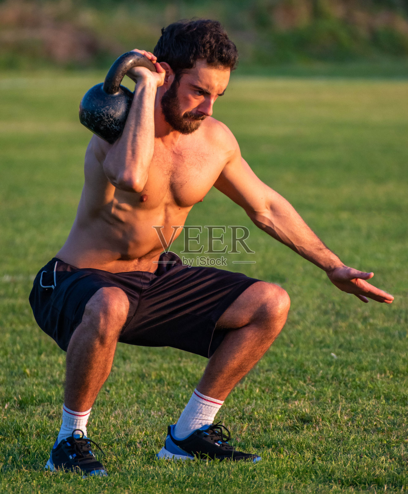 运动员，男子在绿草地上用俄语练壶铃照片摄影图片