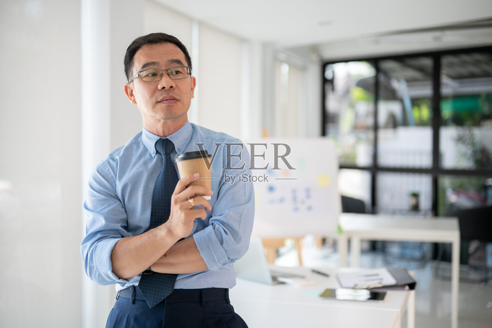 在漫长的一天工作后，有动力的高级商人在喝咖啡休息照片摄影图片