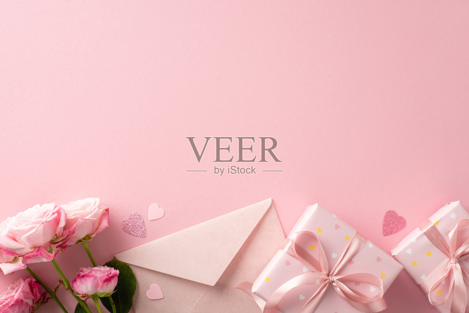 在这个情人节，用俯瞰的方式来分享你的爱。礼品盒，玫瑰，心形纸屑，邀请信封上的淡粉色画布文字或广告空间照片摄影图片