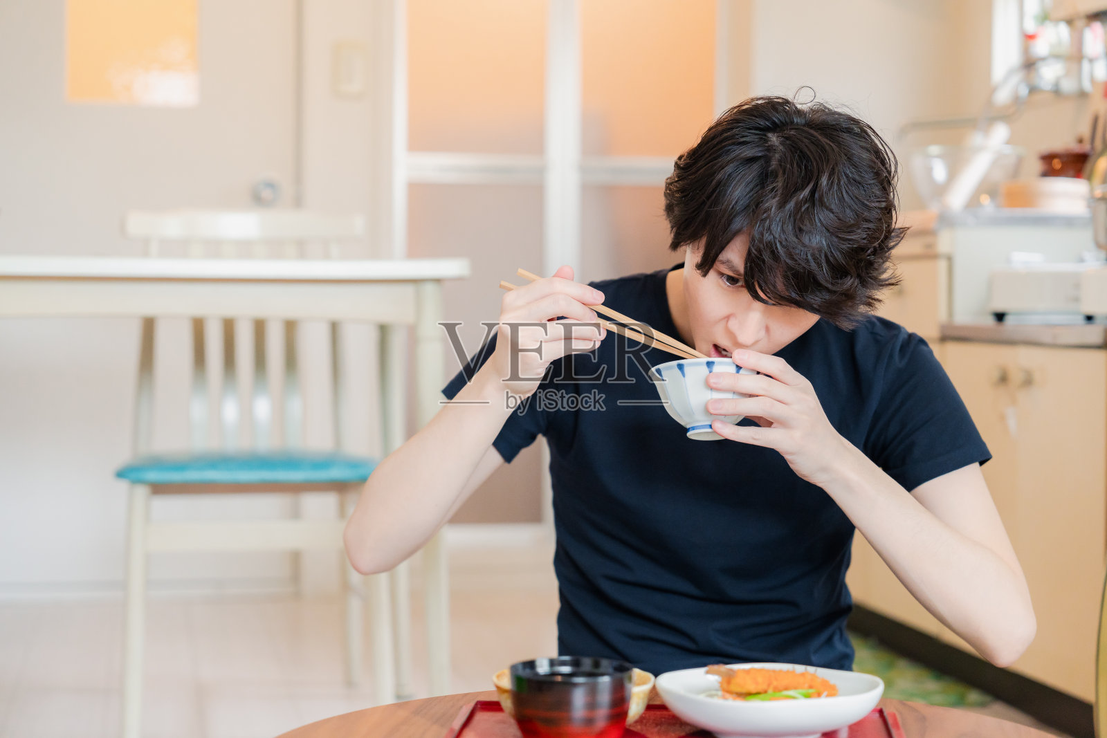 一个年轻人在他独自居住的公寓里吃晚饭照片摄影图片