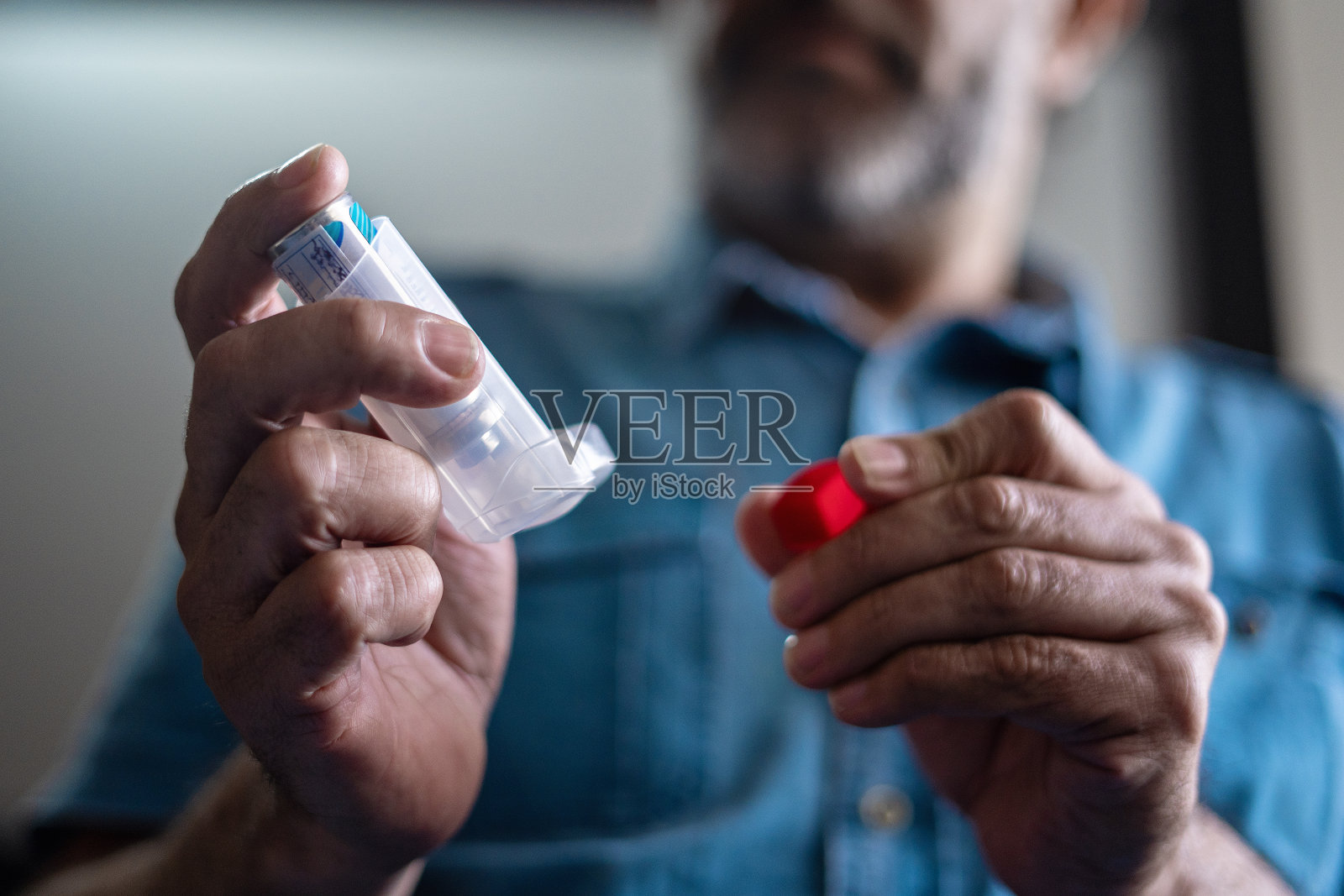 一个老人手持哮喘吸入器的特写镜头。照片摄影图片