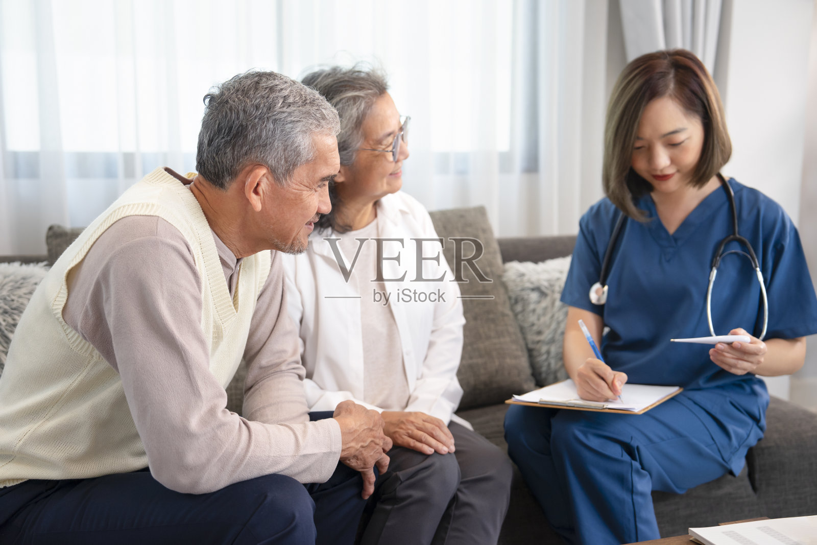 一对亚洲老年夫妇与一位家访护士交谈，年轻的女护士在测量汞含量并做记录照片摄影图片