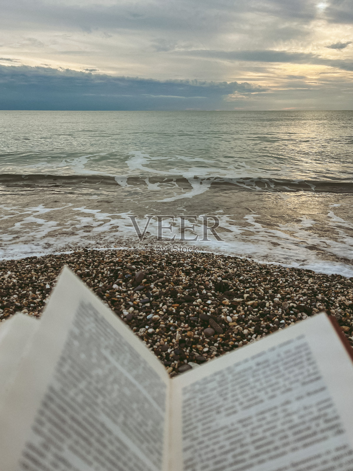 一页打开的书，背景是夕阳下的大海照片摄影图片