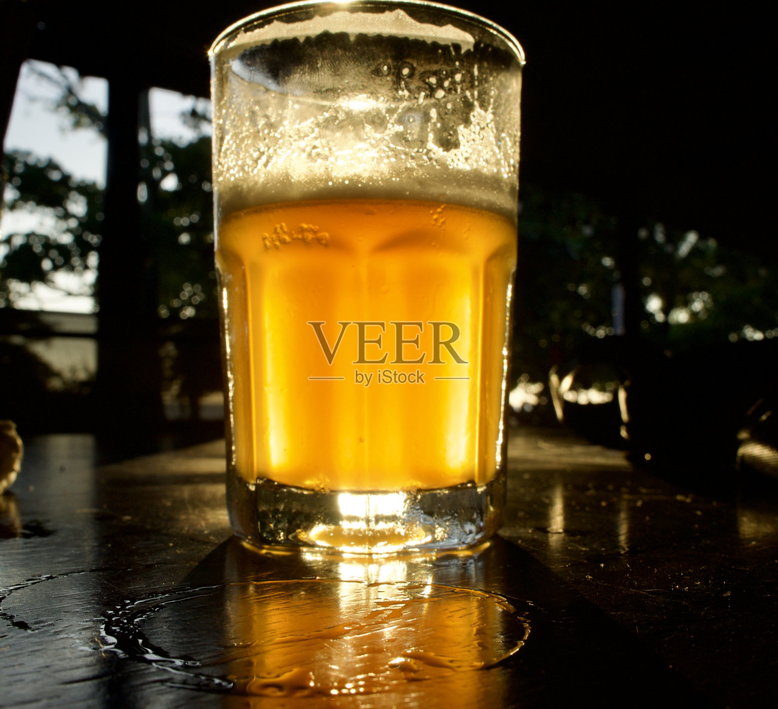 夕阳在一杯印度淡啤酒里。照片摄影图片