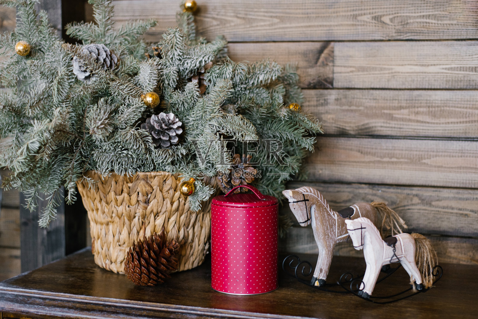 一匹纪念马，一个覆盆子锡罐，背景是柳条篮子里的冷杉树枝。圣诞装饰照片摄影图片