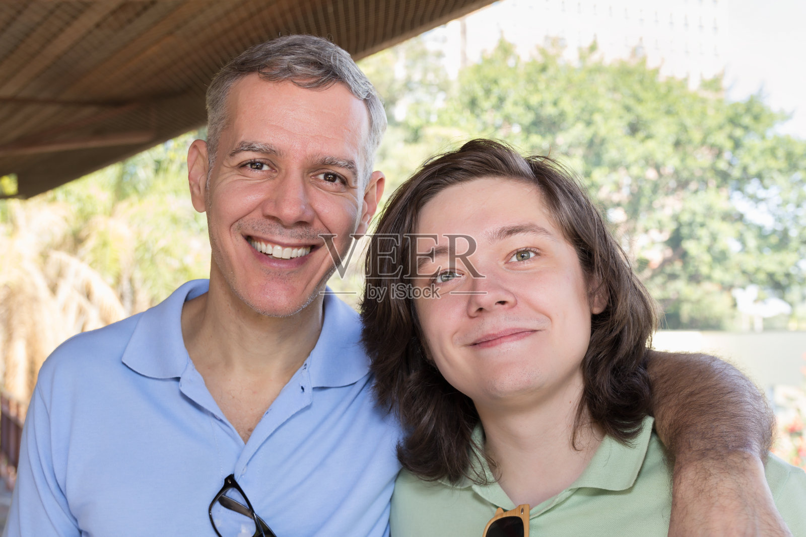 白发苍苍的父亲和年轻的成年儿子微笑着。照片摄影图片