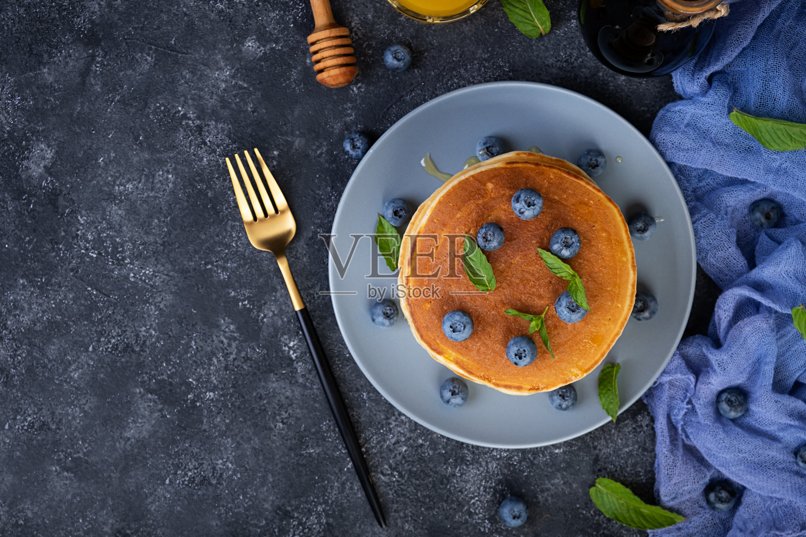 美味的煎饼配蓝莓和蜂蜜。甜煎饼配新鲜浆果照片摄影图片