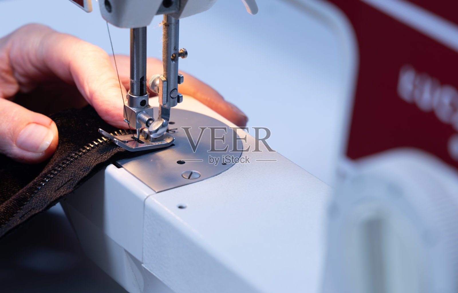 在修理衣服的机器上缝纫。女裁缝在缝纫室的机器上缝纫照片摄影图片