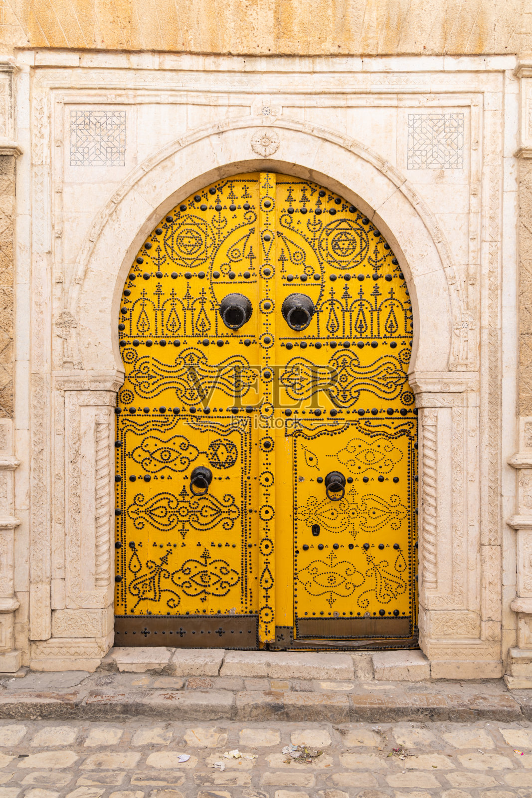 突尼斯露天市场附近一所房子的黄色锁眼或摩尔式拱门。照片摄影图片