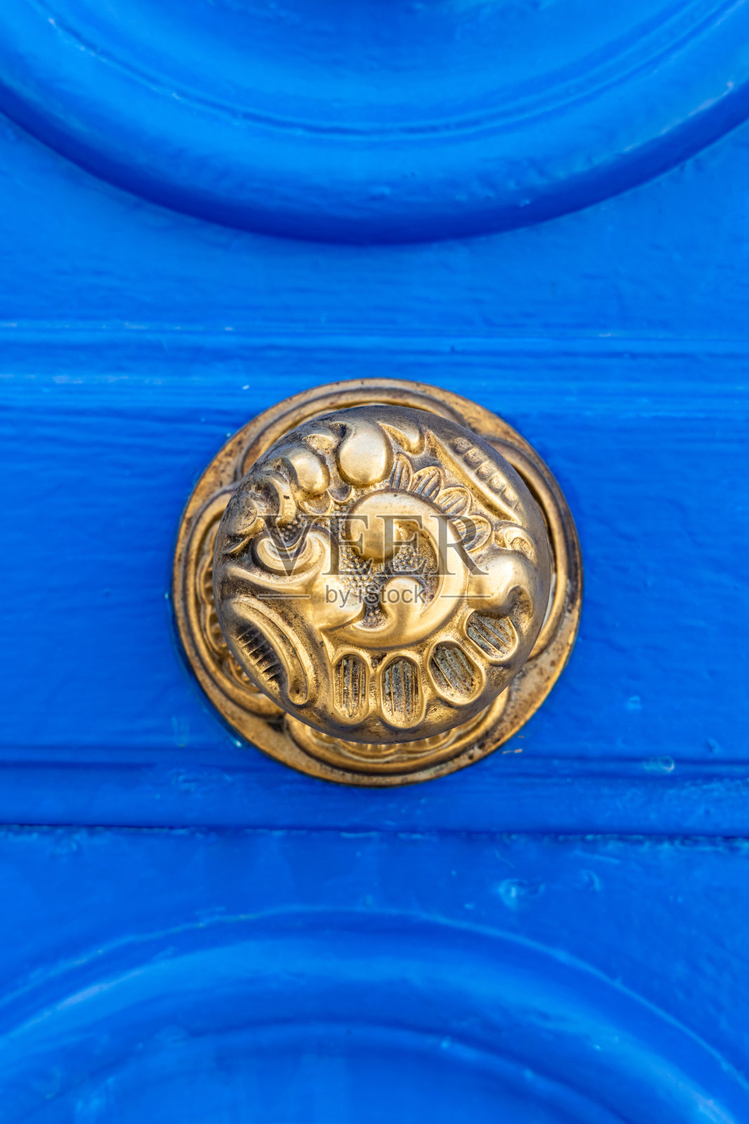 突尼斯露天市场附近一所房子的蓝色门上的黄铜门把手。照片摄影图片