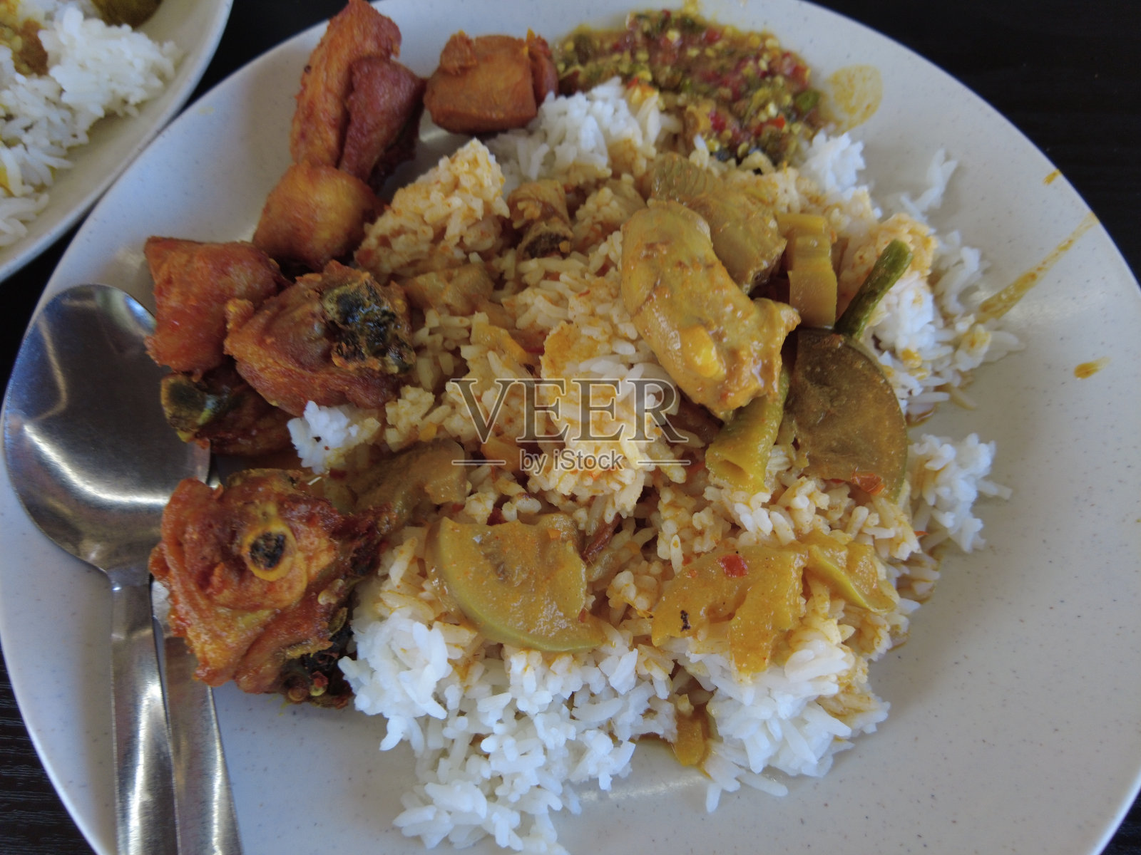 典型的马来西亚菜，一盘热米饭配上黄酱咖喱鱼。照片摄影图片