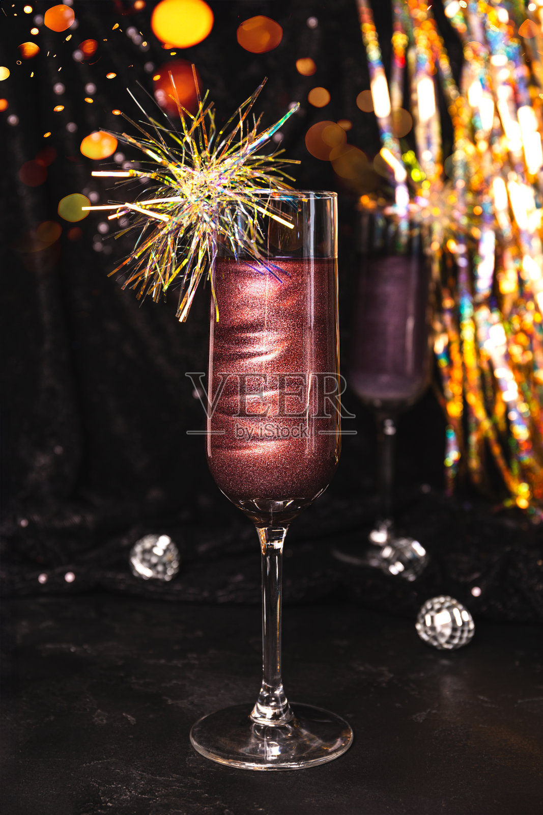 一杯新年鸡尾酒，黑色背景上有可食用的闪光，垂直照片照片摄影图片