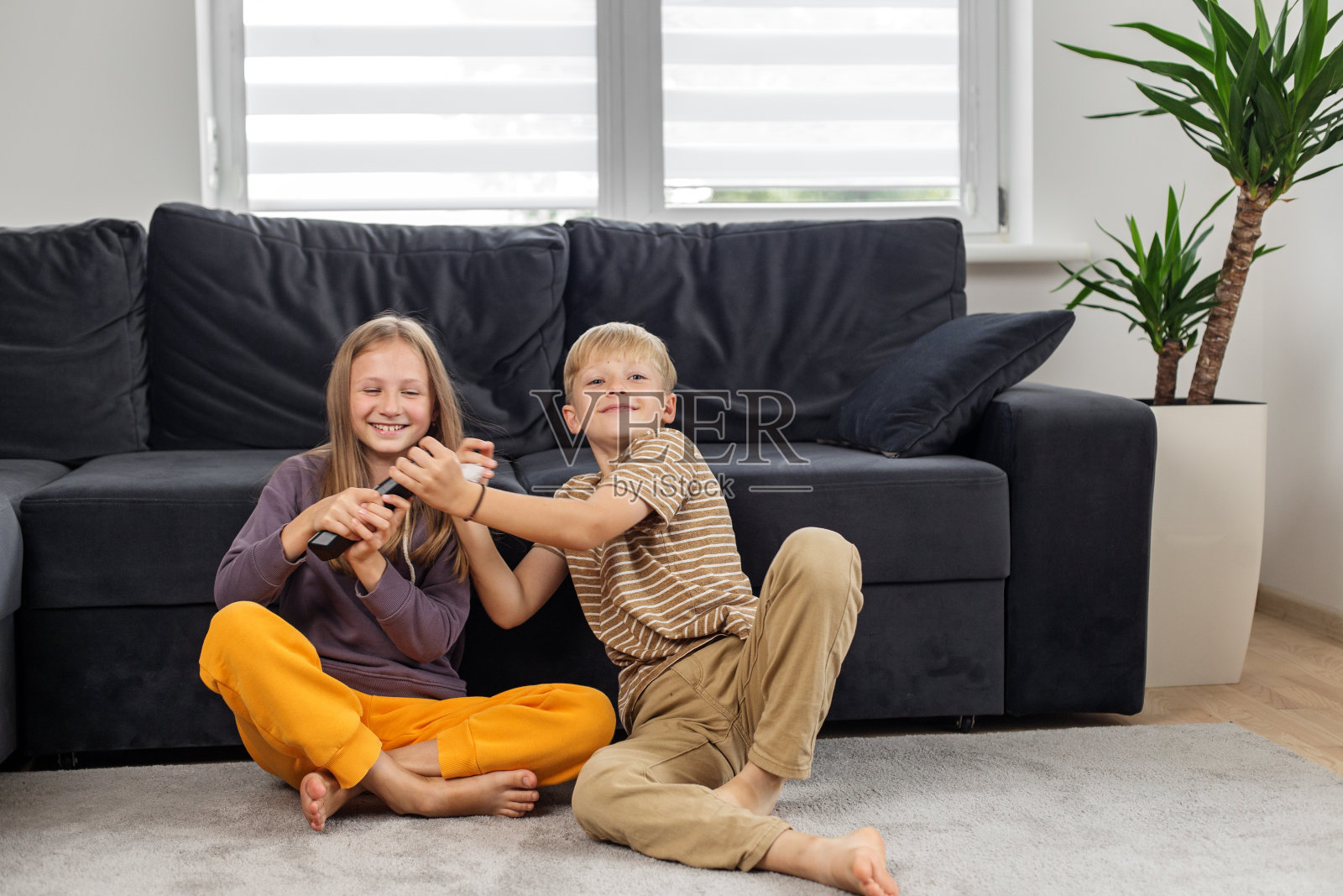 孩子们在家里争抢遥控器。的乐趣。放学后休息。照片摄影图片