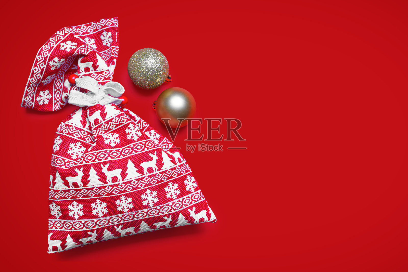 装饰圣诞球和红色礼品袋与圣诞图案在红色背景照片摄影图片