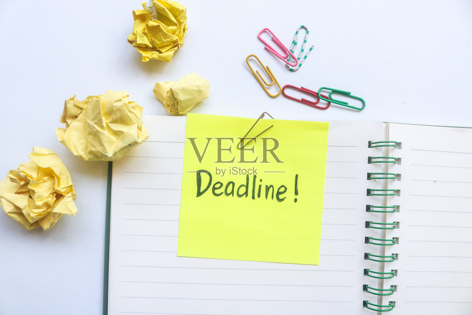“截止日期”这个词写在笔记本顶部的黄色便签上，并被隔离在白色背景上，上面有大量的文字、图像或徽标的复制空间。照片摄影图片