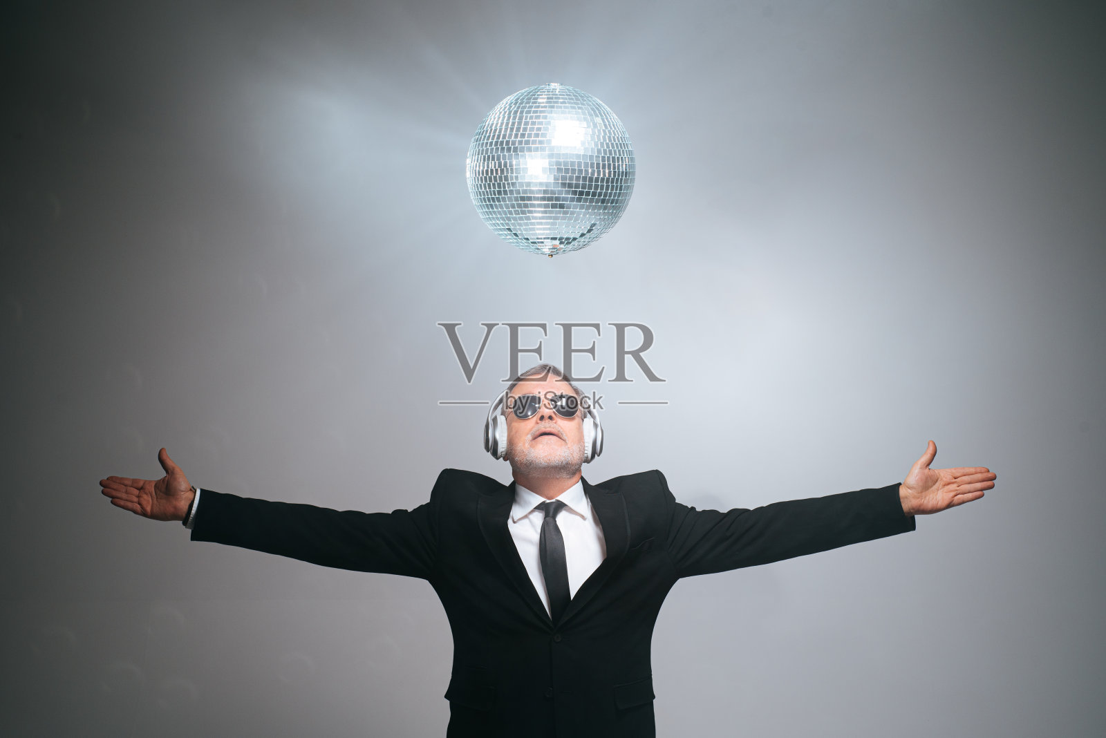 照相馆拍摄的白发商人戴着耳机在镜球下照片摄影图片