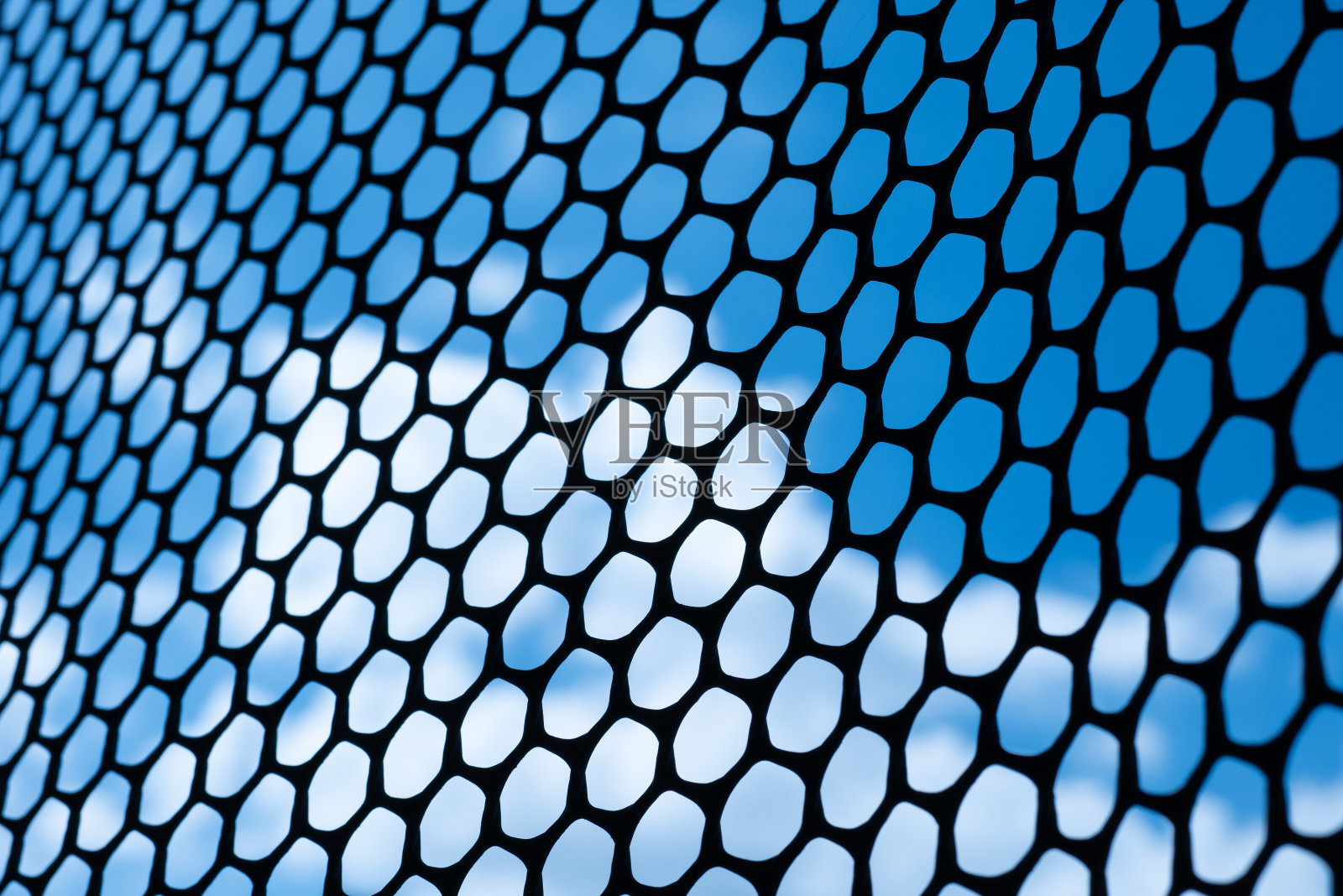 黑钢格栅板上有许多圆孔。电影的那一面看到了天空。照片摄影图片