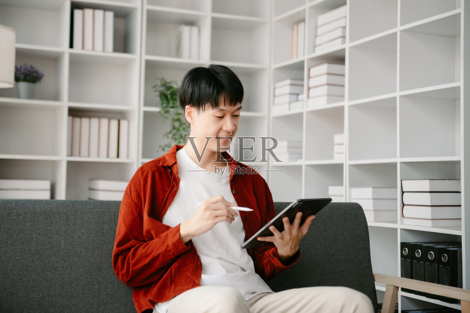 一个亚洲年轻人坐在办公室的办公桌前。照片摄影图片