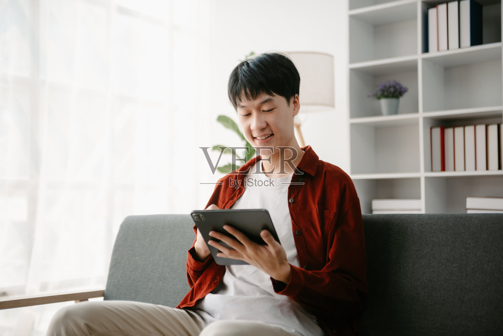 一个亚洲年轻人坐在办公室的办公桌前。照片摄影图片