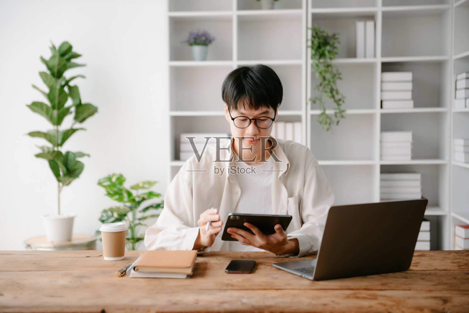 一个亚洲年轻人坐在办公室的办公桌前。照片摄影图片