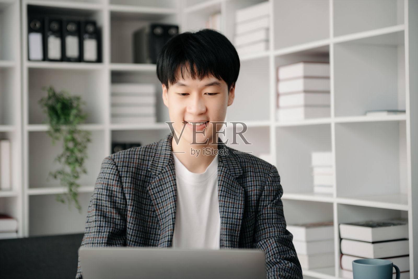 年轻的商人在办公室用笔记本电脑、平板电脑和在纸上做笔记。照片摄影图片