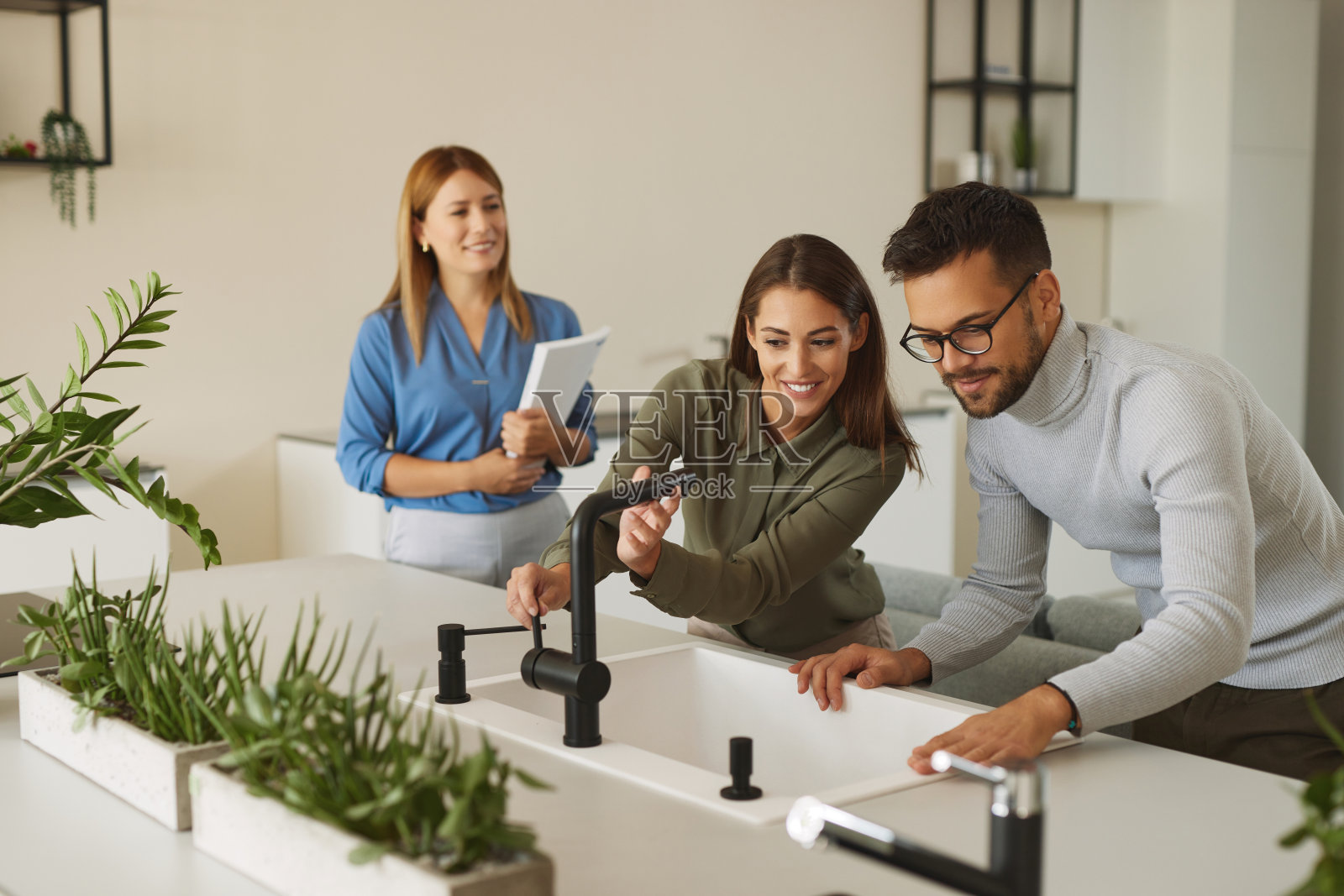 女店员帮助年轻夫妇选择新的厨房水龙头照片摄影图片