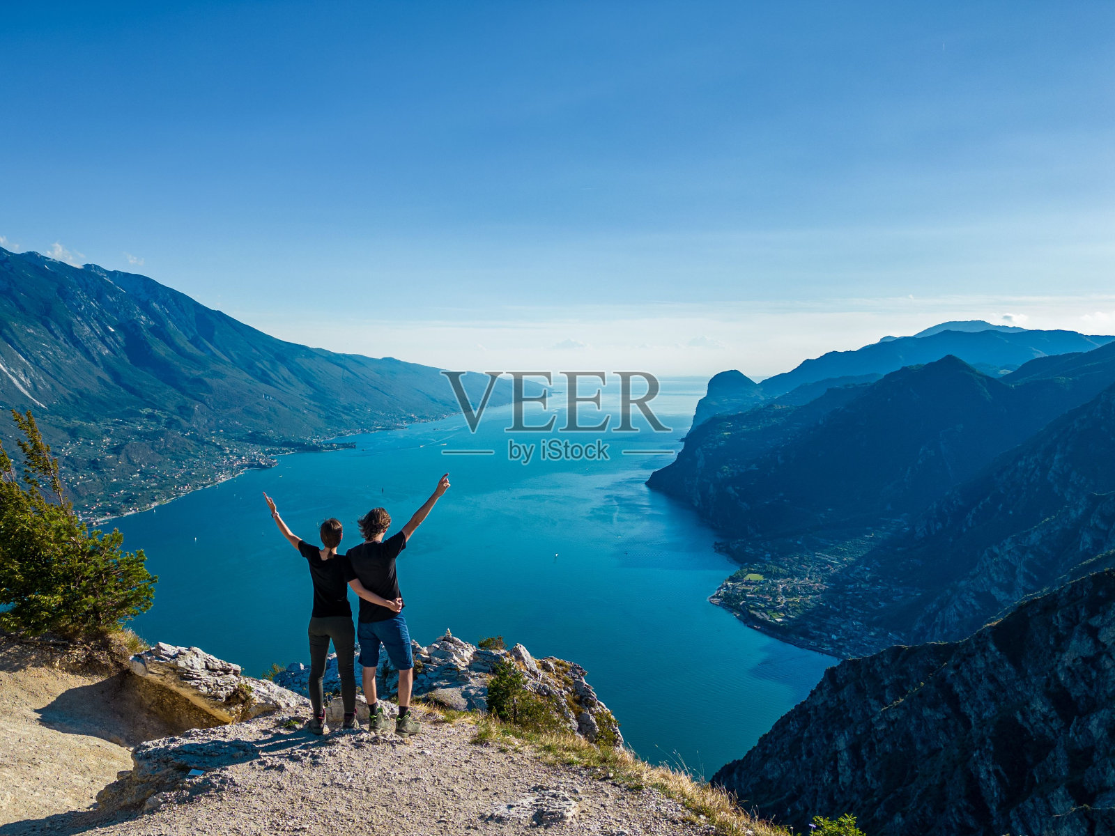 一对夫妇站在山边，双手朝天照片摄影图片