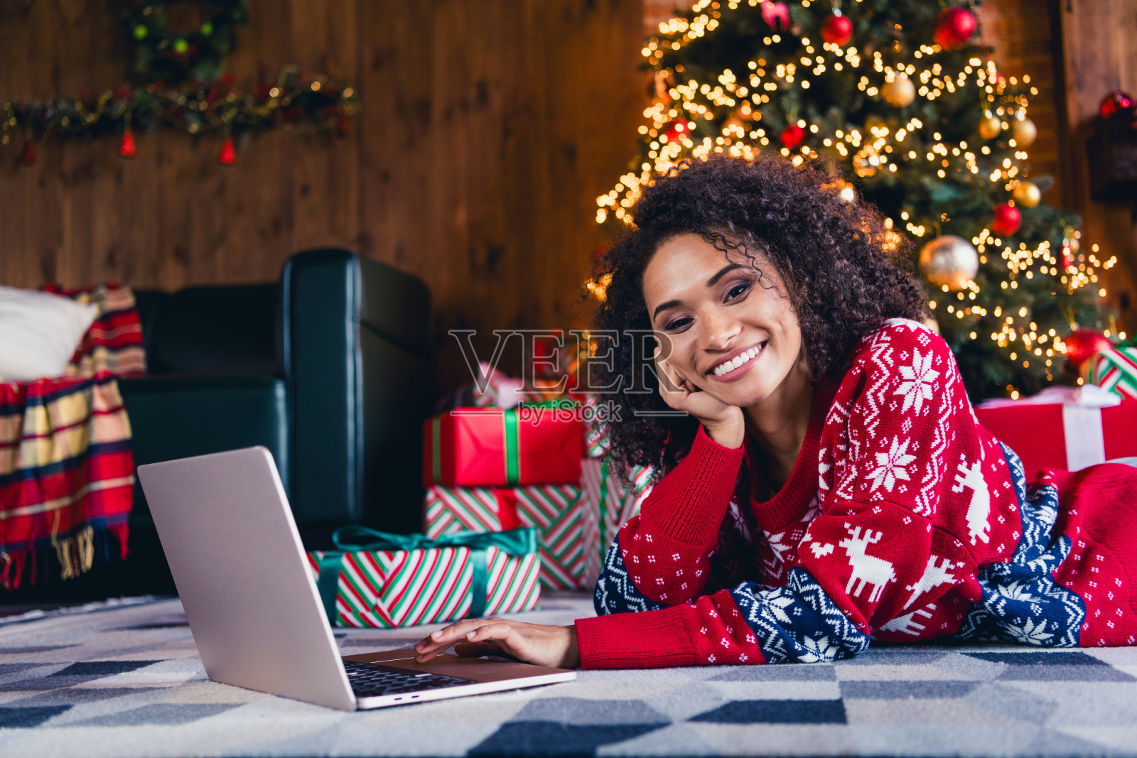 可爱可爱的女孩躺在毛茸茸的地毯上，红色装饰套头衫，在装饰舒适的室内独自度过周末照片摄影图片