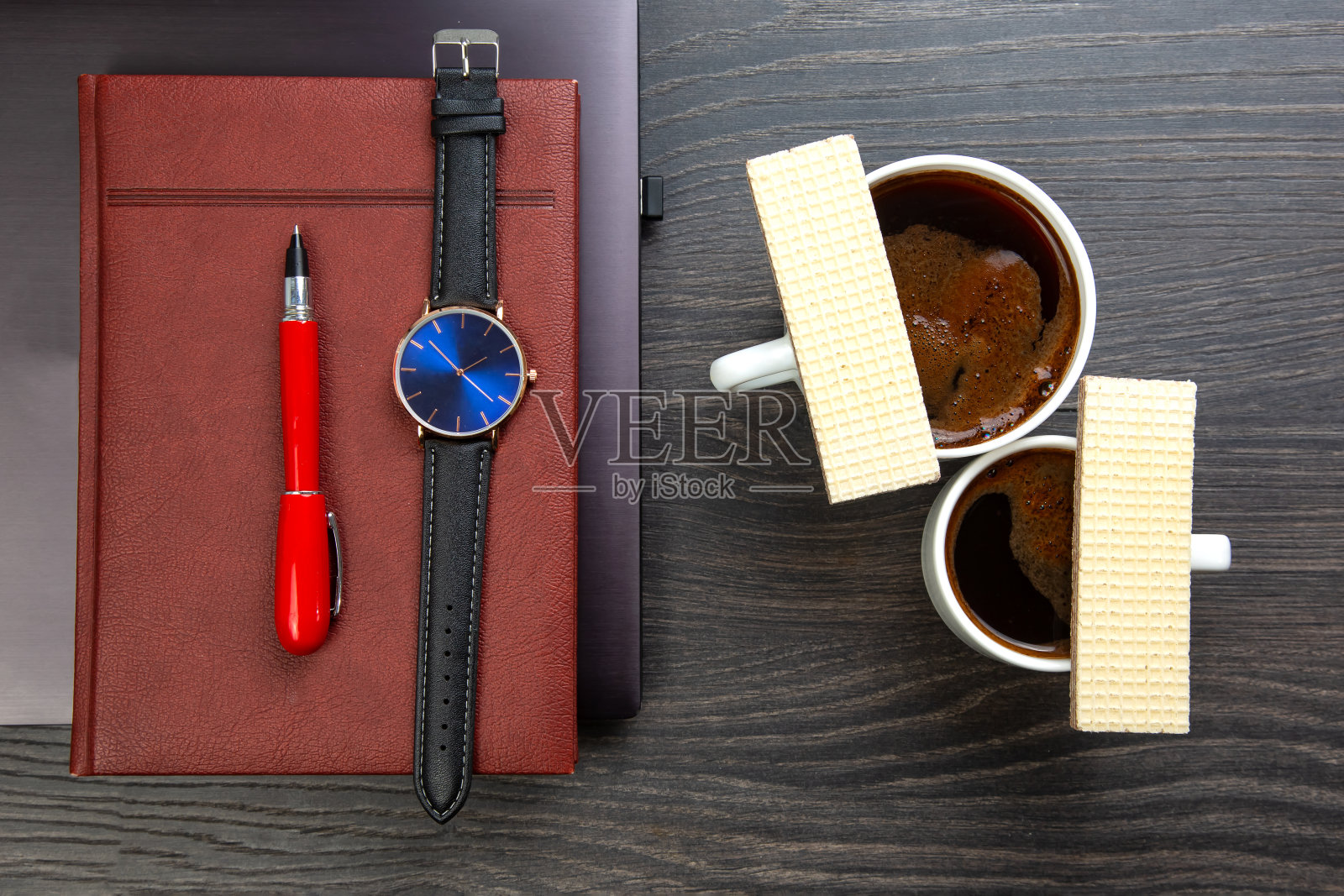 办公室桌子上，笔记本电脑和时钟旁边放着一杯黑咖啡和饼干。商务和早餐时间。照片摄影图片