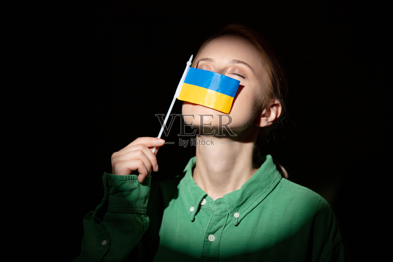 穿着衬衫的时尚女子手持乌克兰国旗，光线聚焦照片摄影图片