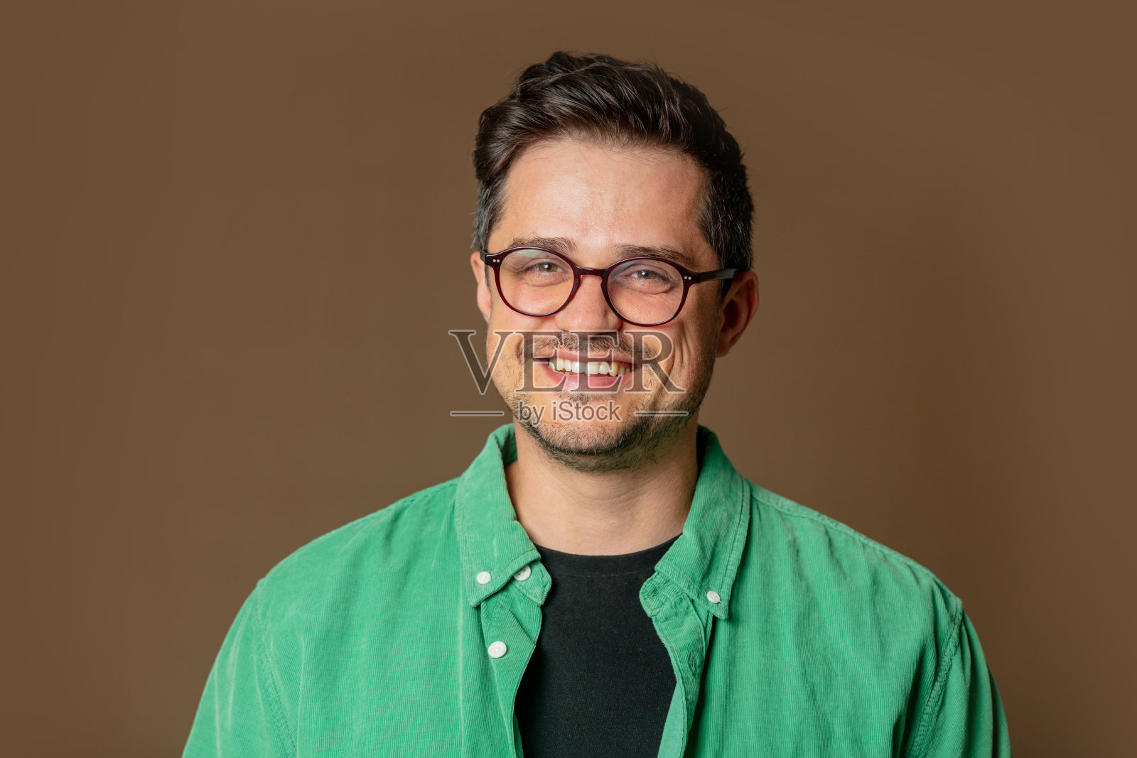 时髦的白人男子，戴着眼镜，穿着棕色背景的绿色衬衫照片摄影图片