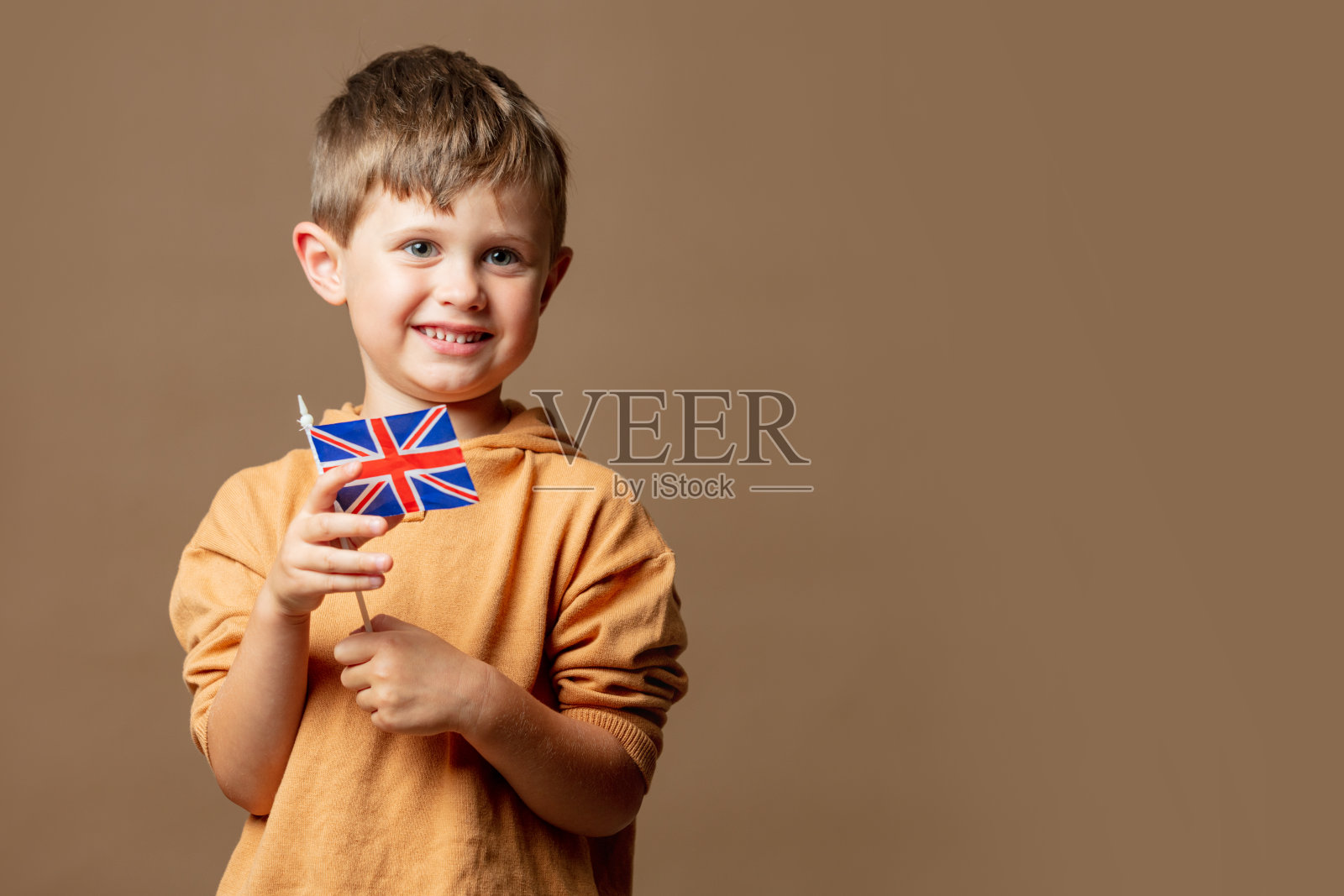 小男孩拿着棕色背景的英国国旗照片摄影图片