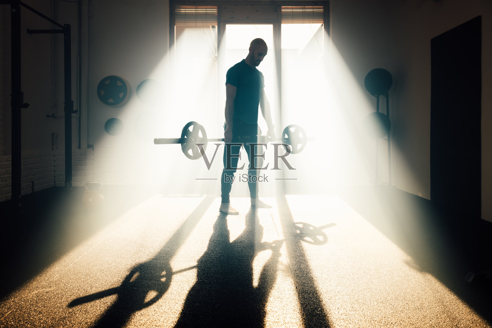 无法辨认的背光男子在健身房举重照片摄影图片