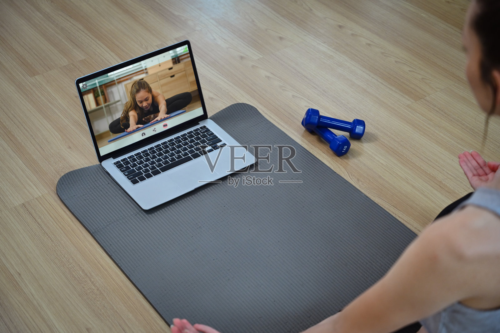 运动的年轻女子在网上做瑜伽，在笔记本电脑上观看在线培训课程照片摄影图片