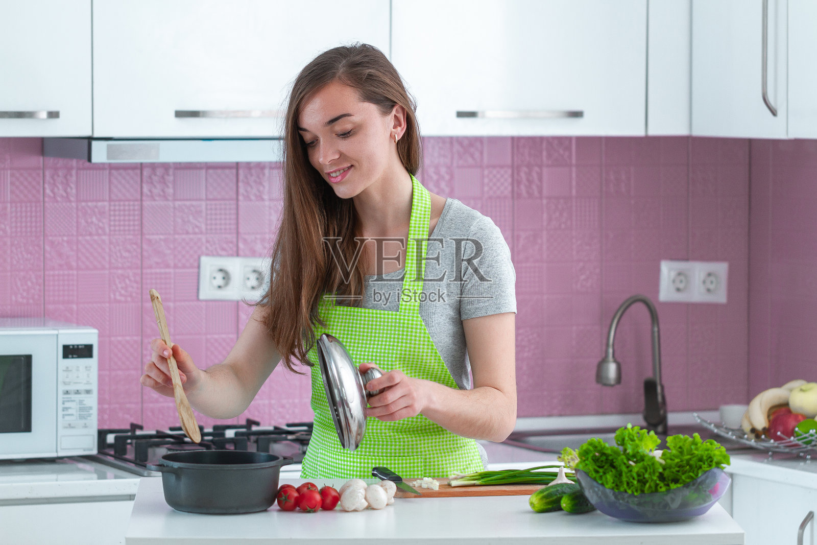 系着围裙的妇女正在厨房里用成熟的蔬菜为家人准备午餐。食物清洁，营养合理。健康的生活方式，饮食照片摄影图片