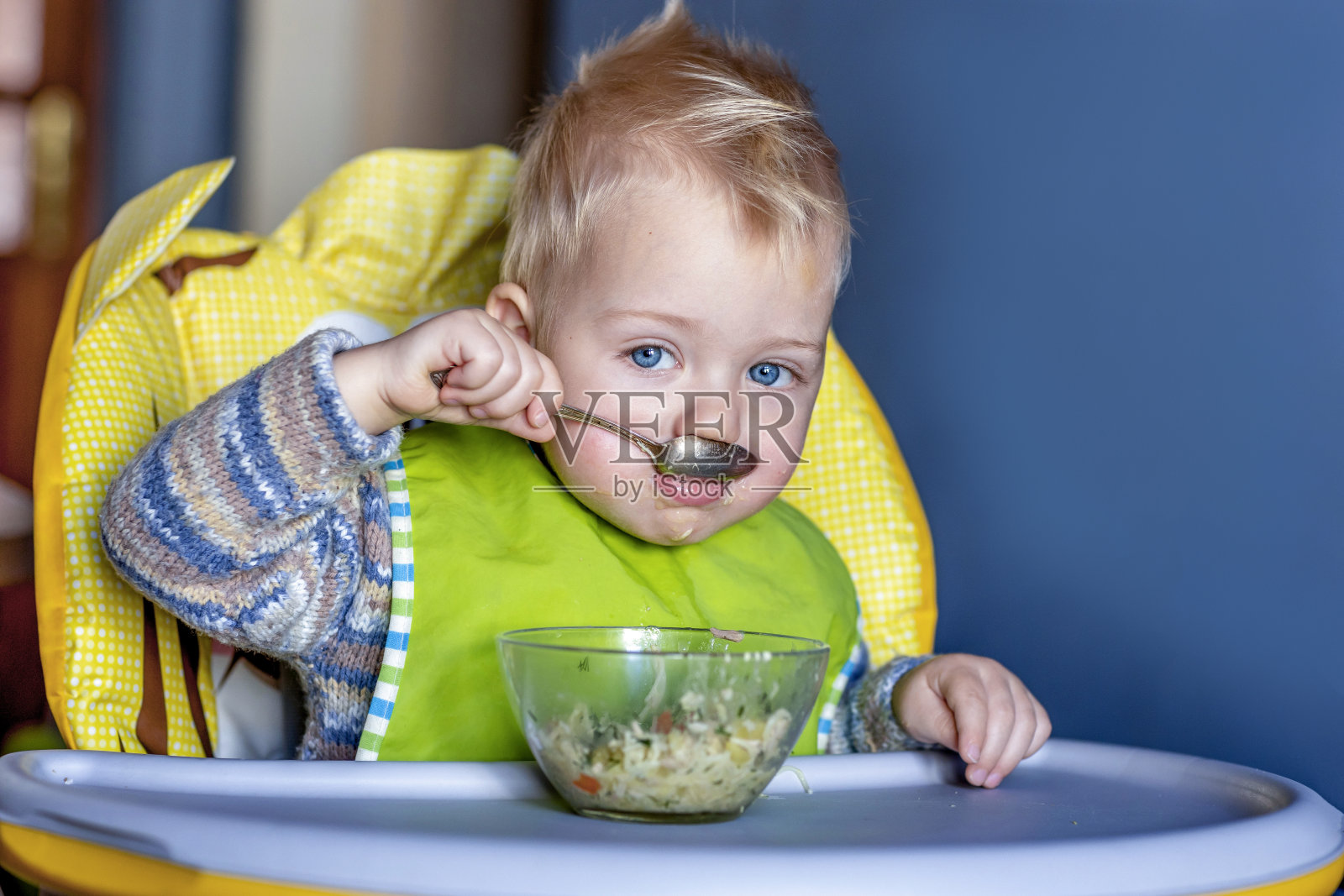 婴儿坐在儿童座椅上独立进食照片摄影图片