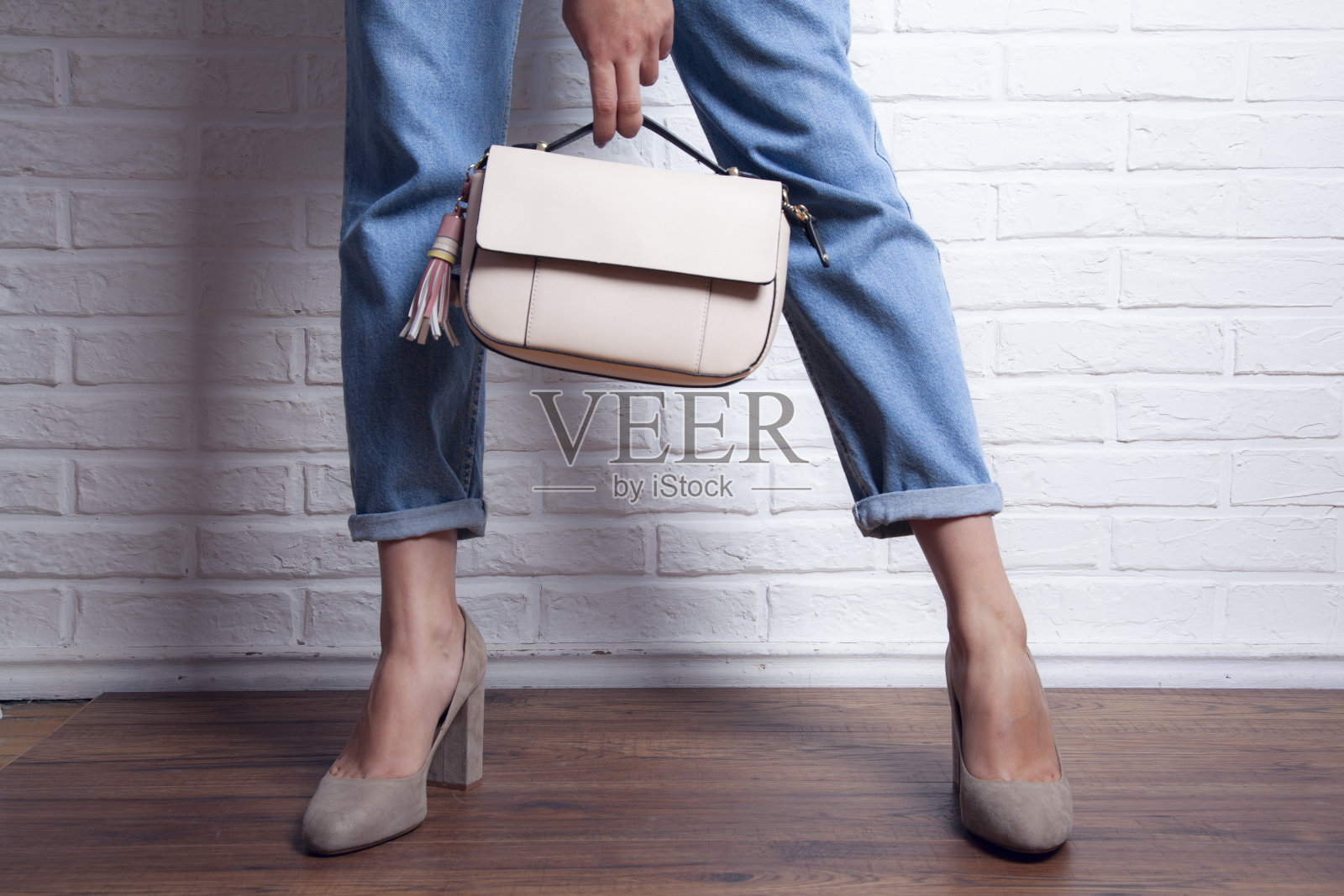 灰色背景下穿着牛仔裤和时尚鞋的女性腿照片摄影图片