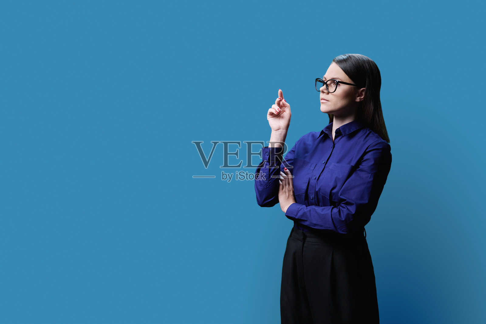 侧面视图，严肃的年轻女子的肖像在蓝色背景上，复制空间照片摄影图片