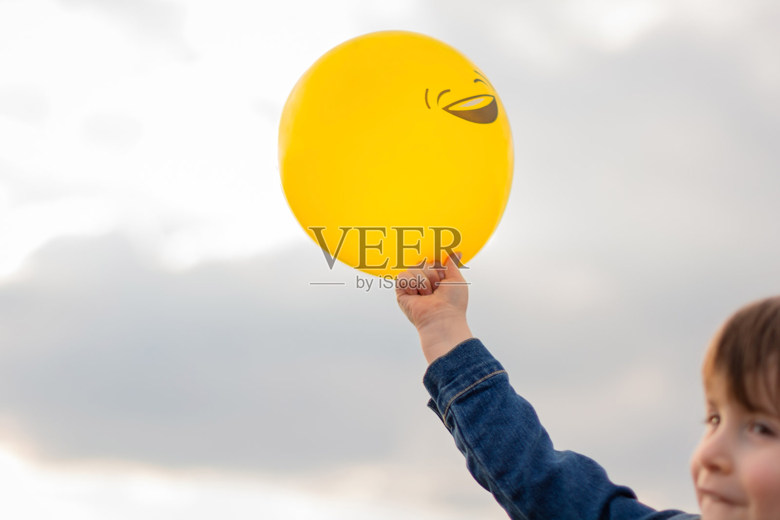 孩子手中的黄色气球对着天空照片摄影图片