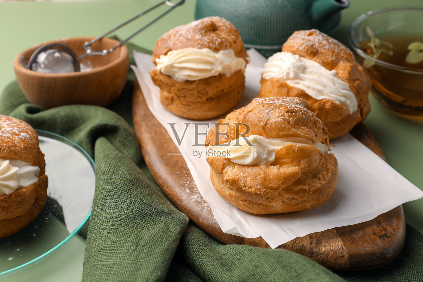 绿色背景下，美味的奶油和茶泡芙照片摄影图片