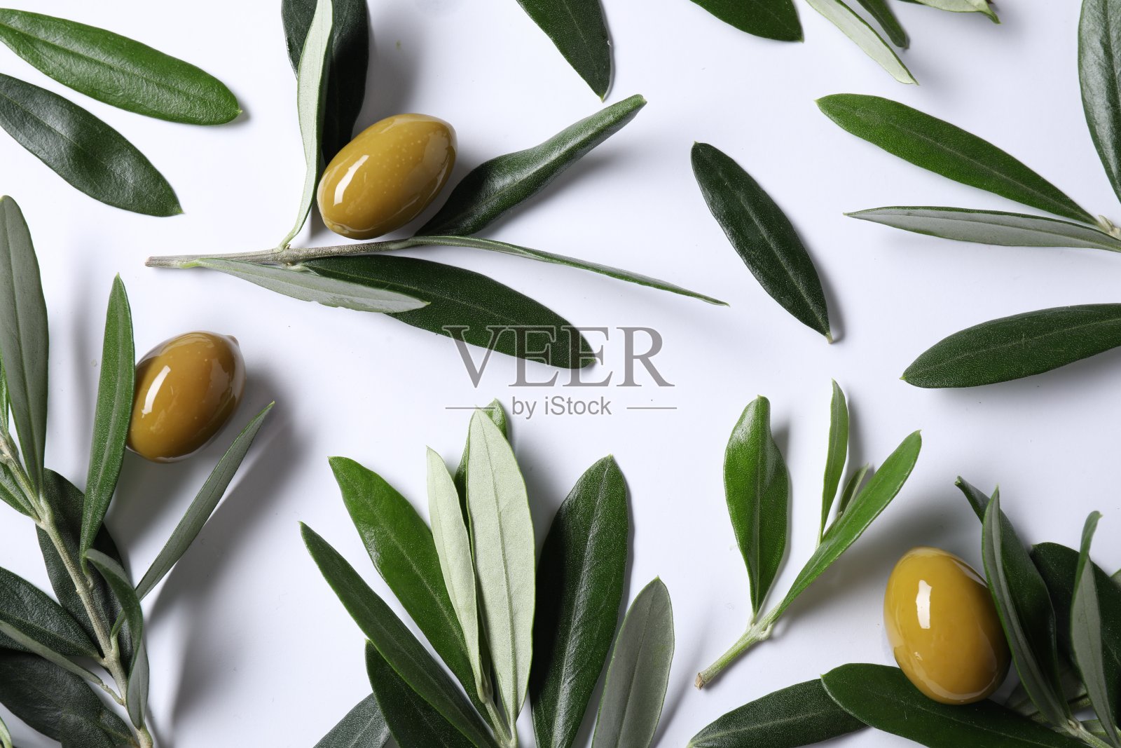 新鲜的绿橄榄和树叶在白色的背景上，平躺着照片摄影图片