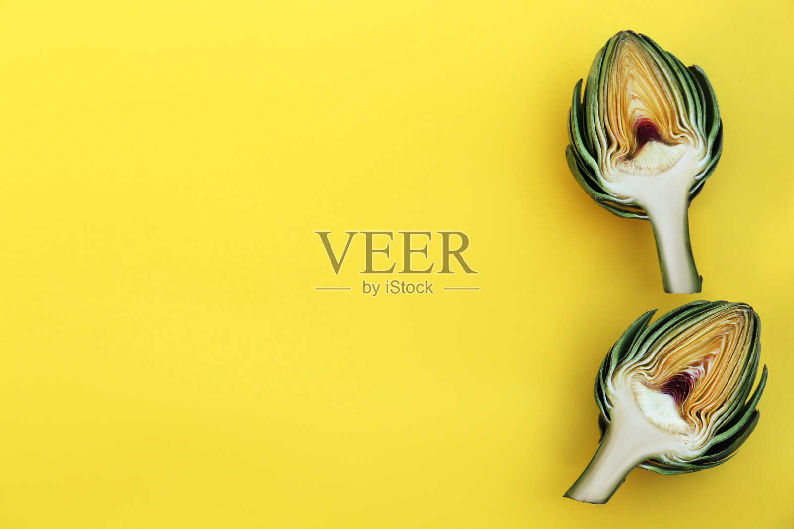 将新鲜的生洋蓟切在黄色背景上，平铺。文本空间照片摄影图片