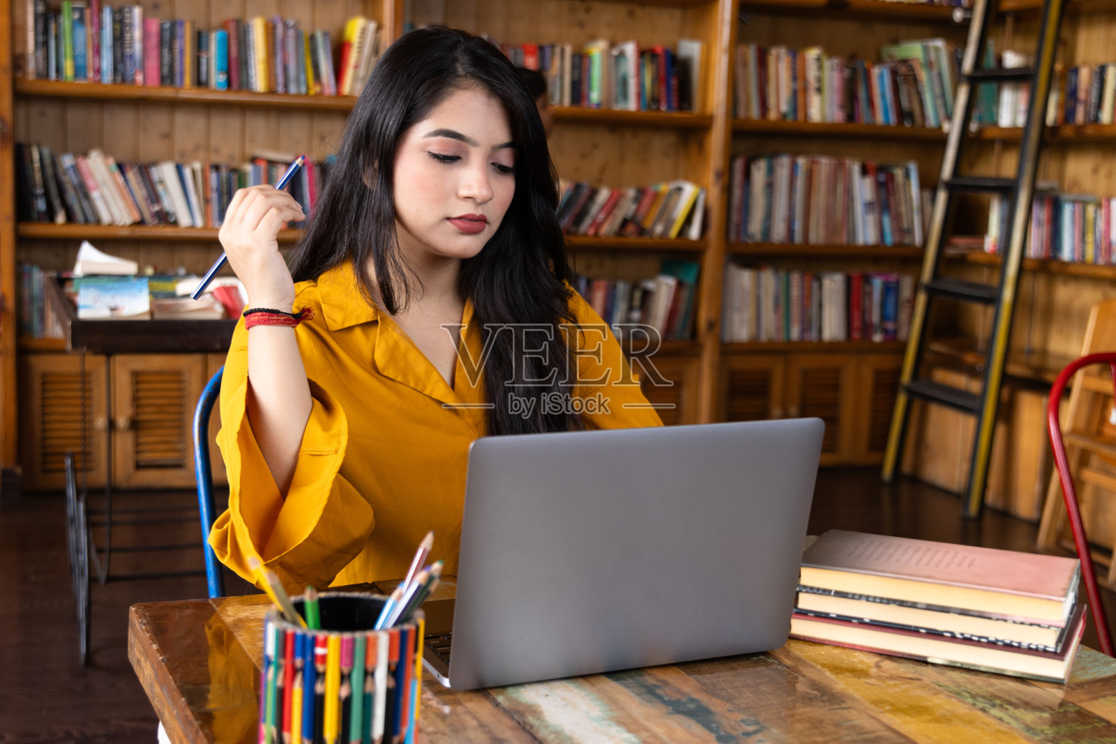 漂亮的年轻女商人，在学校或大学图书馆的笔记本电脑上学习或解释视频电话，或在公司办公室工作，在互联网或书籍上搜索信息照片摄影图片