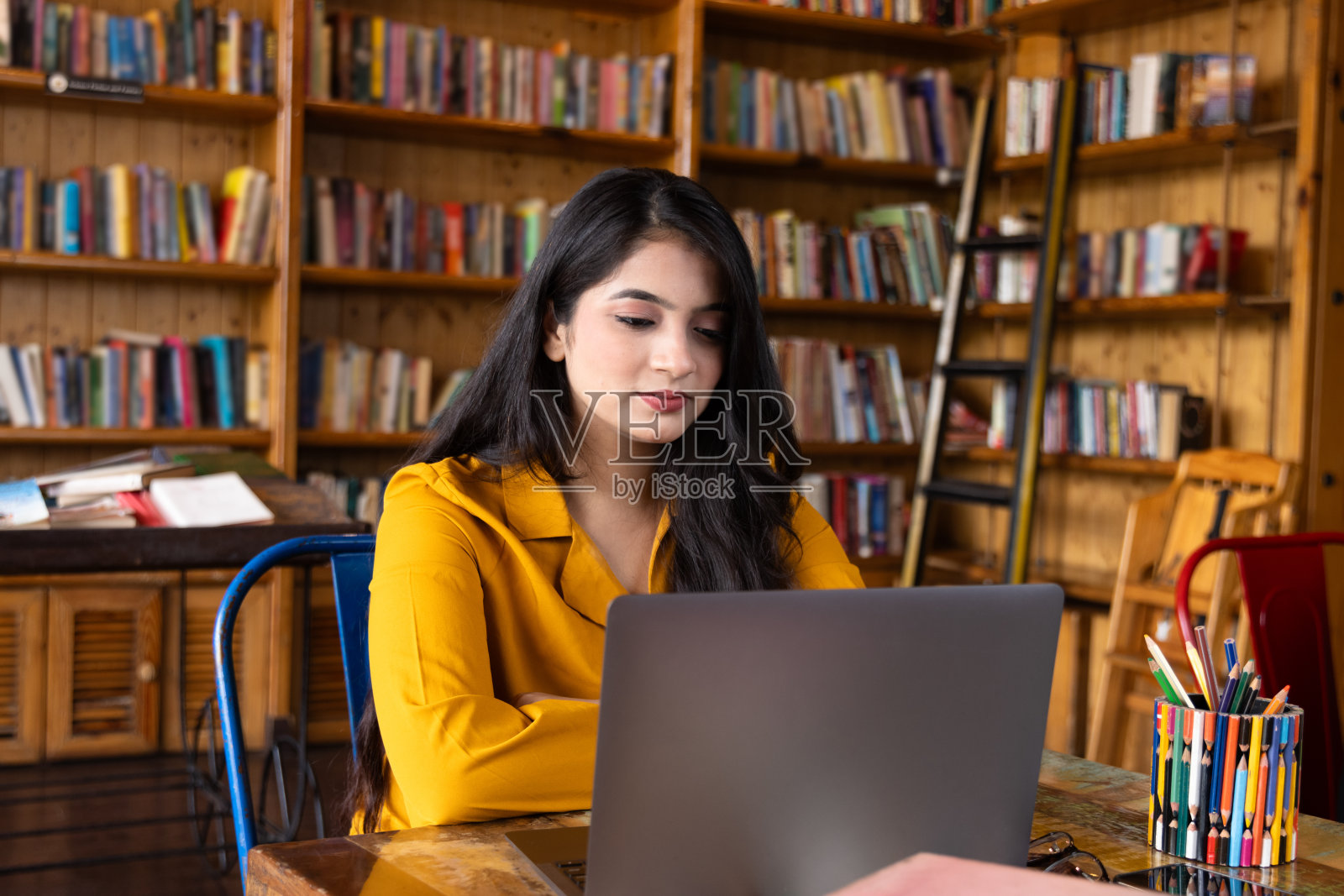 漂亮的年轻女商人，在学校或大学图书馆的笔记本电脑上学习或解释视频电话，或在公司办公室工作，在互联网或书籍上搜索信息照片摄影图片