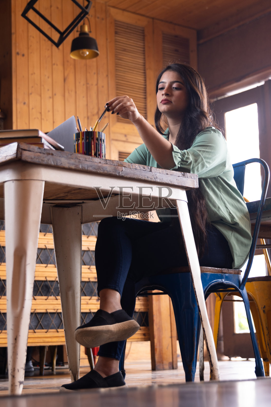年轻的商业女性或女孩或学生在学校或大学图书馆咖啡馆或公司办公室工作或学习，使用笔记本电脑，手持钢笔或铅笔照片摄影图片