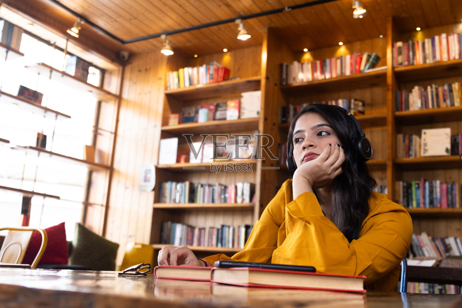 一个漂亮的年轻女孩，商业女性或学生，在学校或大学图书馆或公司办公室工作或学习，坐在书照片摄影图片