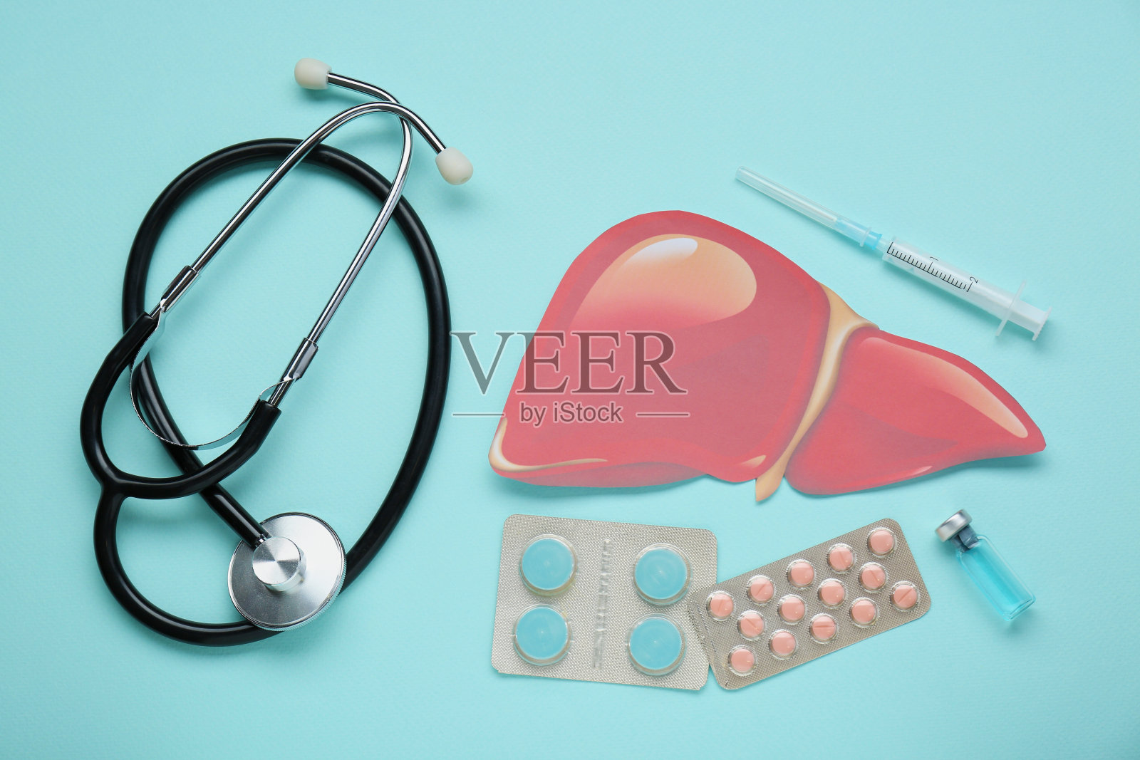 纸肝和医疗用品放在绿松石底色上，平铺。肝炎治疗照片摄影图片